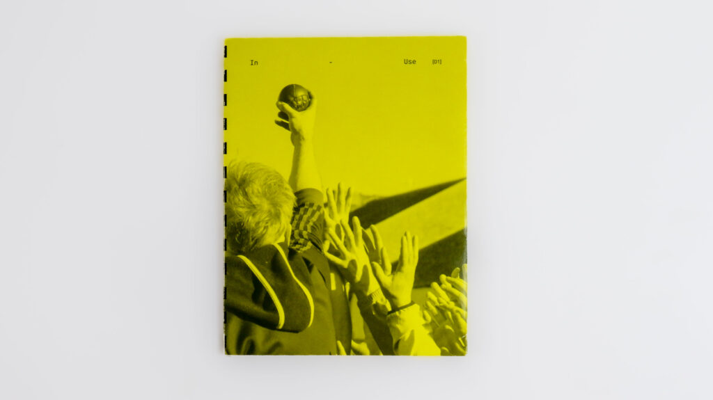 Yellow book cover with a raised hand holding a traditional ball above a crowd of reaching hands.