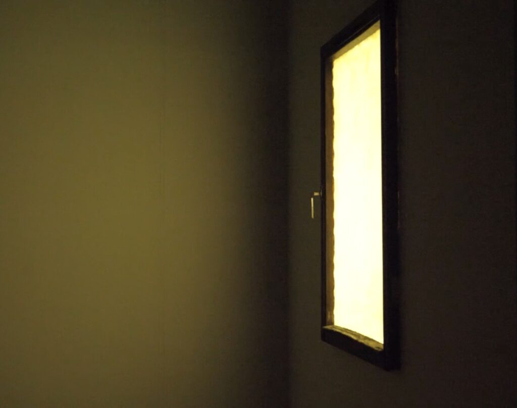 Window frame with stretched latex replacing glass, illuminated from behind, casting light into a room.