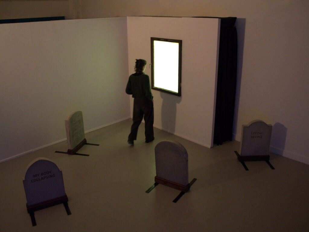 Person standing in front of a window illuminating a room with four gravestones.