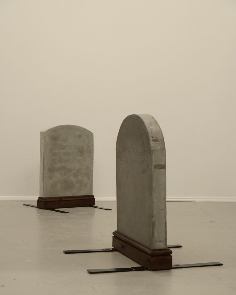 Two Gravestones standing in a white exhibiting space.
