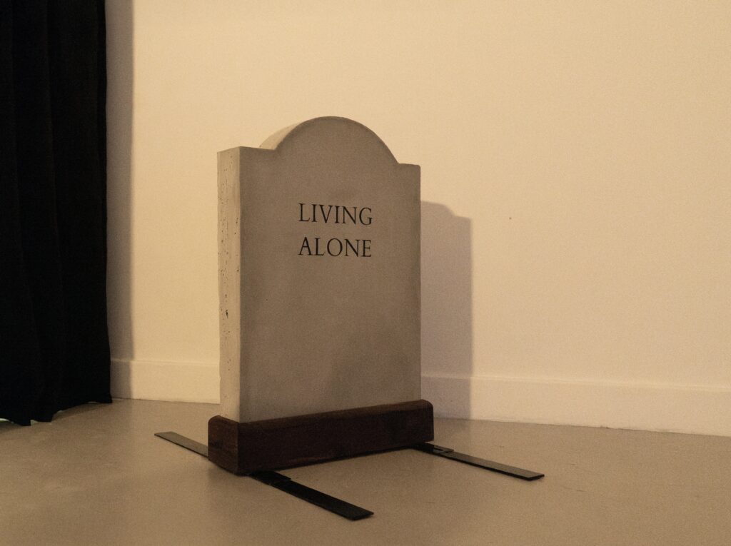 Gravestone with text reading 'Living Alone'