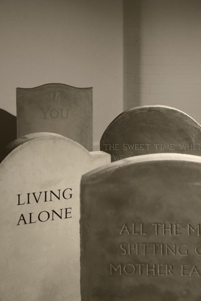 Multible gravestones standing behind each other, one reading Living Alone