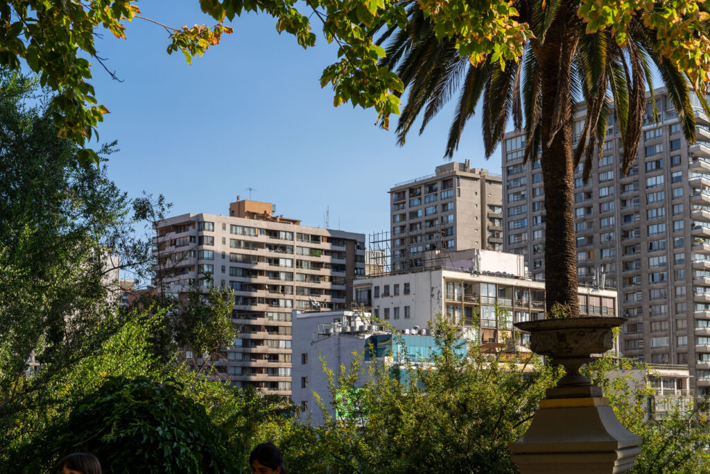 A leafy public park with palm trees frames high-rise flats in the centre of Santiago.